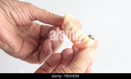 closeup of an older womans hand holding dentures Stock Photo