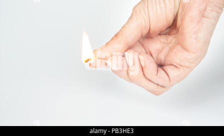 closeup of an older womans hand holding a burning matchstick Stock Photo
