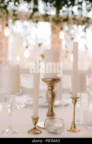 White candles on a wedding table. Gentle and stylish details of decoration of a wedding celebration Stock Photo
