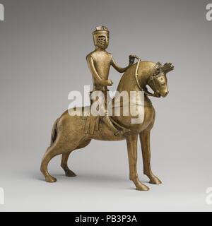 Aquamanile in the Form of a Mounted Knight. Culture: German. Dimensions: Overall: 14 11/16 x 12 7/8 x 5 5/8 in. (37.3 x 32.7 x 14.3 cm)  Weight PD: 146.5oz. (4153g). Date: ca. 1250.  Aquamanilia, from the Latin words meaning 'water' and 'hands,' served to pour water over the hands of priests before celebrating Mass and of diners at table. This aquamanile, in the form of a horse and rider, exemplifies the courtly ideals of knighthood that pervaded Western medieval culture and influenced objects intended for daily use.  It depicts a type of armor that disappeared toward the third quarter of the  Stock Photo