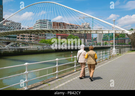 Women friends, rear view of two stylish mature women walking alongside the River de Bilbao in Bilbao, Northern Spain. Stock Photo