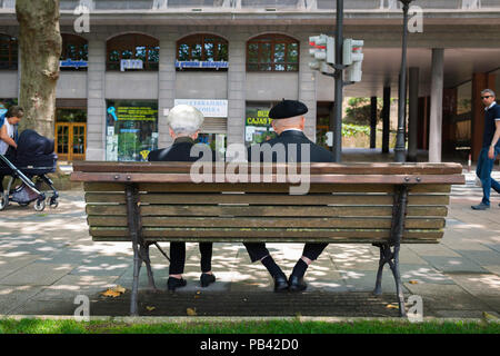 Basque people Spain, rear view of a senior married Basque couple sitting together on a bench in the center of Bilbao, Northern Spain. Stock Photo