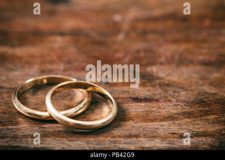 A pair of golden wedding rings on wooden background, copy space Stock Photo