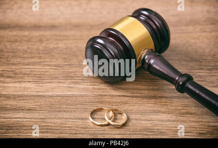 Divorce concept. Wedding rings and judge gavel on wooden background, copy space Stock Photo
