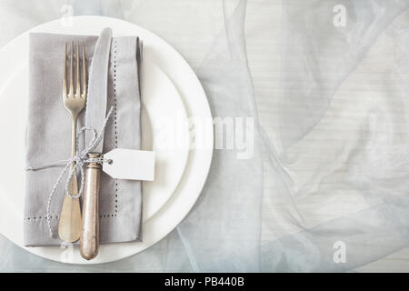 Holiday dinner. Table place setting with plates, silver fork and knife and blank white tag, copy space Stock Photo
