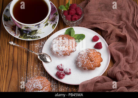 Capcake with raspberries and sugar powder on the table with tea teapot Stock Photo