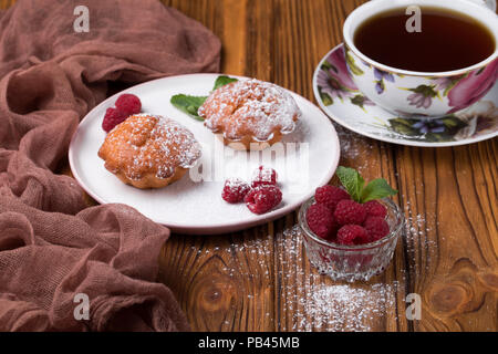 Capcake with raspberries and sugar powder on the table with tea teapot Stock Photo