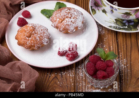 Capcake with raspberries and sugar powder on the table with tea teapot Stock Photo