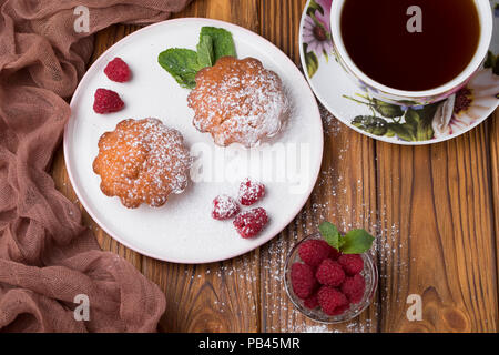 Capcake with raspberries and sugar powder on the table with tea teapot Stock Photo
