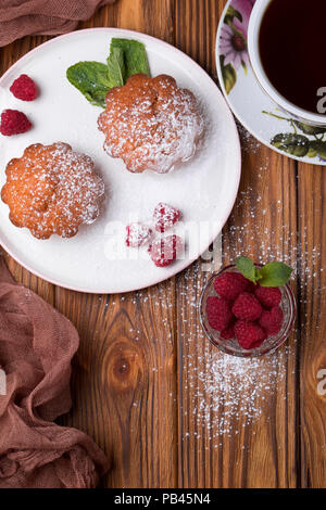 Capcake with raspberries and sugar powder on the table with tea teapot Stock Photo