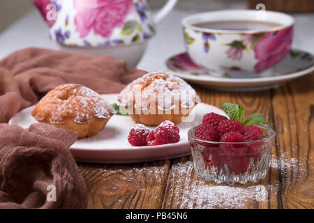 Capcake with raspberries and sugar powder on the table with tea teapot Stock Photo