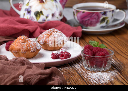 Capcake with raspberries and sugar powder on the table with tea teapot Stock Photo