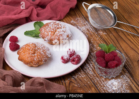 Capcake with raspberries and sugar powder on the table with tea teapot Stock Photo