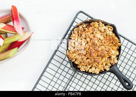 Homemade cooked rhubarb and apple crumble with oatmeal in the cast iron pans Stock Photo