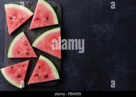 Fresh colorful sliced watermelon on black stone background, top view Stock Photo