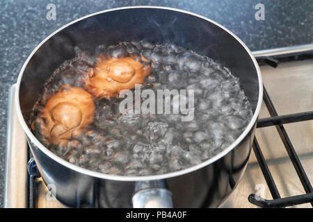 Two eggs boiling in a pan on a gas cooker / stove Stock Photo