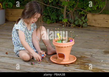 young girl playing with her fairy garden outside on the decking Stock Photo
