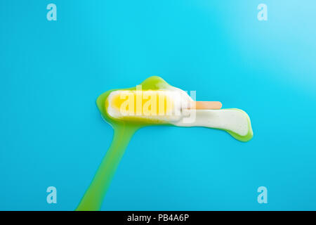 yellow popsicle in a melting process on blue background Stock Photo