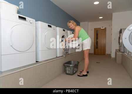 Woma using a drying machine in a laundry room. Stock Photo