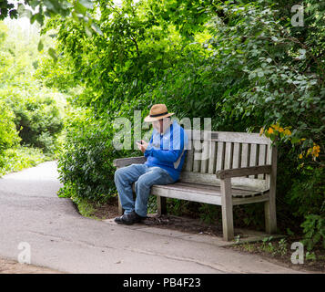 Man sitting alone on a park bench in Camden, Maine Stock Photo