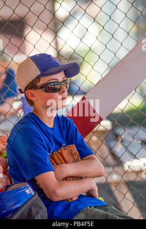 12 Year old boy, holding glove, looking thoughtfull, close up, wearing hat, blue jersey and red shoes, sunglasses. Model Relese #105 Stock Photo