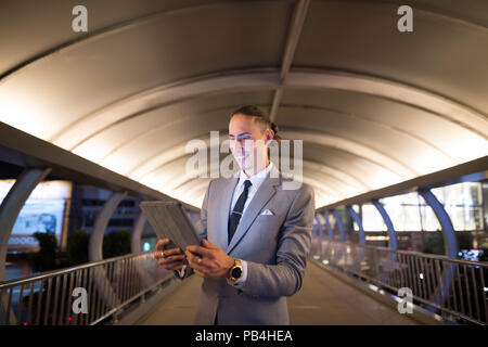 Businessman Outdoors At Night Using Digital Tablet Stock Photo