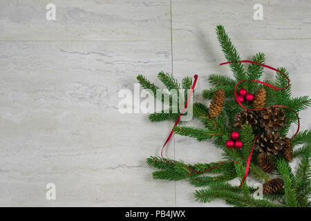 Five spruce and three Scotch pine pinecones along with two clusters of red berries and red ribbon  on a spruce bough in the bottom right corner with c Stock Photo