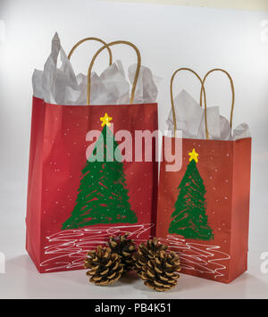 Two red gift bags decorated for Christmas and ready for giving along with four pine cones Stock Photo