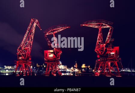 Illuminated old port cranes on a boulevard in Szczecin City at night, color toning applied, Poland. Stock Photo