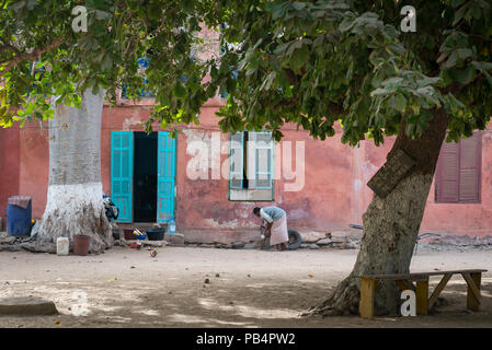 A woman sweeping the outside of her home on Goree island. Senegal Stock Photo