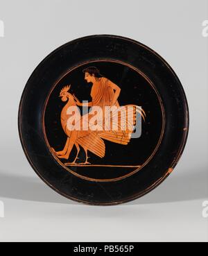 Terracotta plate. Culture: Greek, Attic. Dimensions: Diam.: 7 3/8 in. (18.7 cm). Date: ca. 520-510 B.C..  Youth riding rooster  Plates were favored by some of the major vase-painters, both black-figure and red-figure, during the last decades of the sixth century B.C. The tondo presented the same challenge as the interior of a cup. This young man astride a rooster touches the bird's neck with his right hand and, curiously, rests his toes on the framing circle. The meaning is not evident, but the reference undoubtedly has to do with the rooster as a love gift. Museum: Metropolitan Museum of Art, Stock Photo
