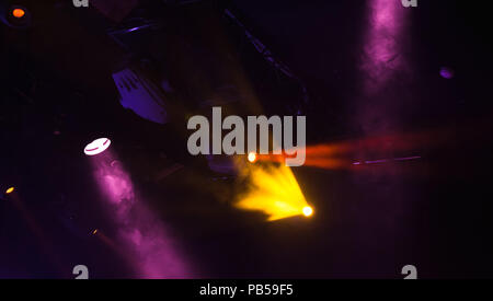 Spot lights with strong beams in smoke over dark background, modern stage illumination equipment Stock Photo