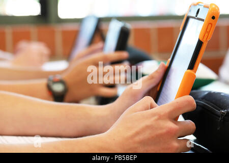 High school students working on using an ipad tablet style electronic computer device. modern pedagogy and teaching learning in education educational Stock Photo