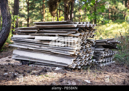 environment pollution - stack of old asbestos slate roof sheets in forest Stock Photo