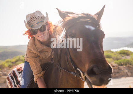 beautiful cheerful young woman enjoy and ride her brown cute horse in friendship and relationship. animal lover and pet therapy concept. travel and va Stock Photo