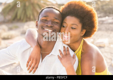 happy beautiful black race african couple in love or friendship stay together walking hugged with big smilies under the sunlight of the summer in vaca Stock Photo