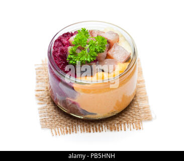 Herring  salad with colorful vegetables in a small glass jar isolated on white Stock Photo