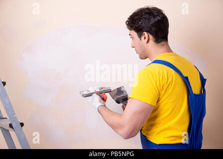 Young contractor employee applying plaster on wall Stock Photo