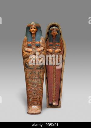 Mummy Board of the Singer of Amun-Re, Henettawy. Dimensions: L. 171.3 cm (67 7/16 in.); W. 40 cm (15 3/4 in.); D. 16 cm (6 3/8 in.). Dynasty: late Dynasty 21. Date: ca. 1000-945 B.C..  Henettawy's principal burial equipment consisted of two splendid coffins (25.3.182a, b; 25.3.183a, b) and a mummy board (25.3.184). The coffins and the mummy board are all shaped like wrapped mummies with elaborate masks fastened over the heads.  The mummy board has no pectoral on a necklace. There are, however, two emblems of the scarab that pushes the sun disk, the lower one flanked by two Re-Harakhty falcons  Stock Photo