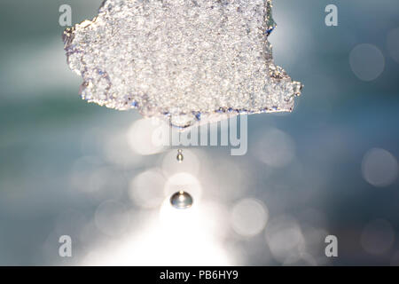 Hand holding a piece of broken ice up in the sun Stock Photo