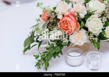 Beautiful flowers and greens and also small glass candlesticks. A stylish decor on a wedding table Stock Photo