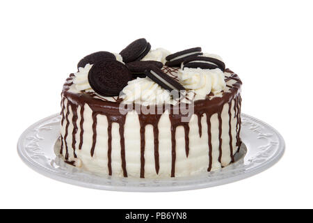 White whipped cream frosted cake with chocolate cream filled sandwich wafer cookies, melted chocolate melting down the sides on a porcelain plate, iso Stock Photo