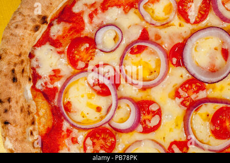 Hot pizza close-up. Cheese onion and tomato on scorched sourdough base. Classic Italian comfort food. Stock Photo