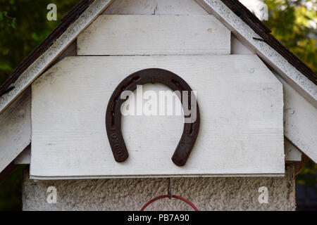 Rusty old horseshoe on painted white wood background - Garden decoration Stock Photo