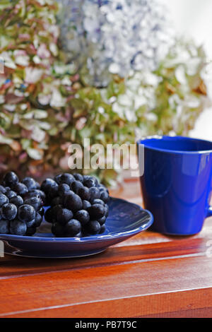 Still life of grapes and flowers on table Stock Photo
