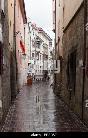 Buildings reflecting on the pavement on a rainy day along the narrow street of Badgasse in Innsbruck, Austria Stock Photo