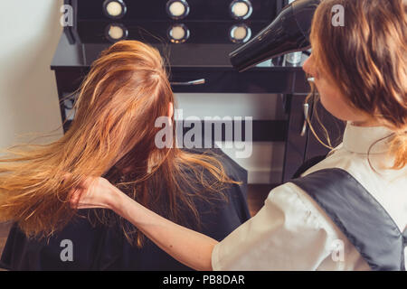 Beautician blow drying woman's hair at beauty salon Stock Photo