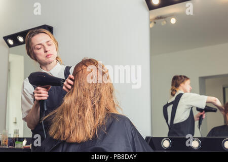 Beautician blow drying woman's hair at beauty salon Stock Photo