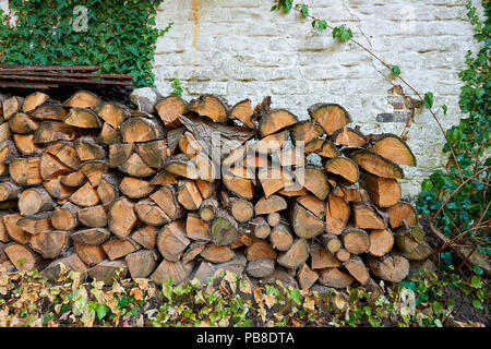 Stack of wooden logs against grungy and rustic wall Stock Photo