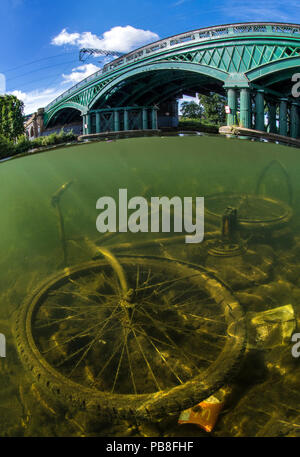 Discarded bicycle in the River Nene, Peterborough, Cambridgeshire, England. UK August.  The bridge was build by William Cubitt in 1850 and is the only cast iron bridge still in use on a major high speed train line. Stock Photo